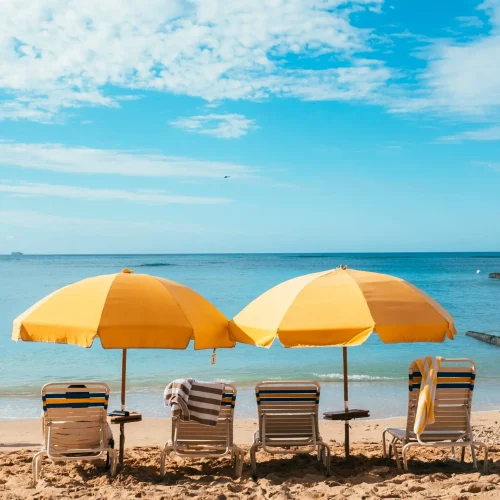 Yellow Beach Umbrellas And Deck Chairs Set On A Beach On A Sunny Day